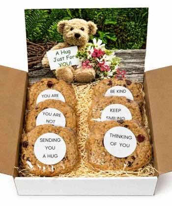 A gift box filled with gourmet cookies with inspirational messages and a large gift card that says A Hug Just for You