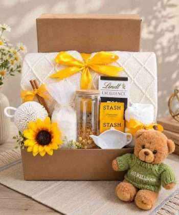 Cozy get well gift box with knitted blanket, teddy bear, herbal tea, chocolate, bath salts, glass tumbler, and comfort gifts.